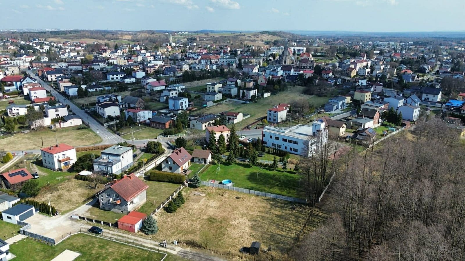 Panorama Imielina z drona z widoczną w dolnej części działką budowlaną na sprzedaż na tle domów i kościoła.